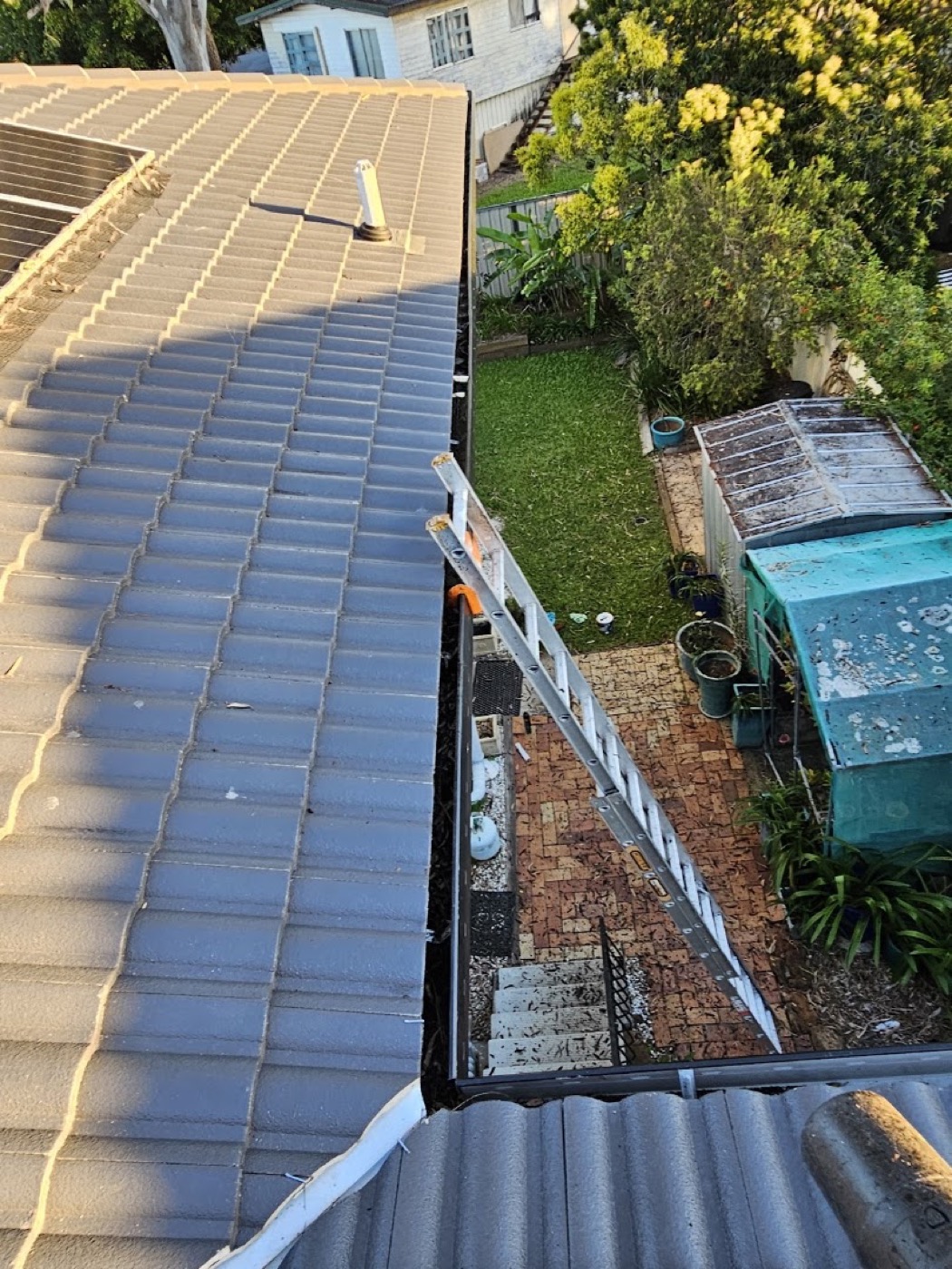 A Colorbond roof and gutter line looking down over a backyard