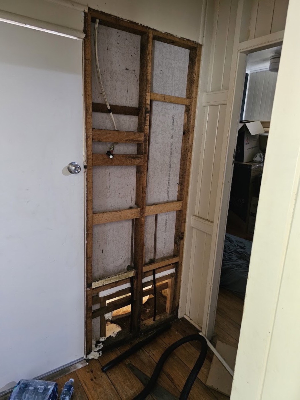 A wall opened back to its timber studs beside a doorway