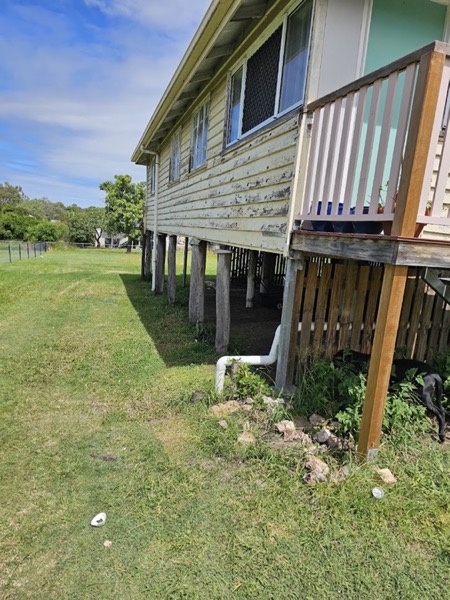 A high-set house on stumps with a timber deck and balustrade