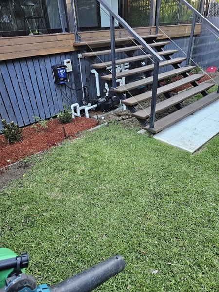 Timber deck stairs and a downpipe beside a mown lawn