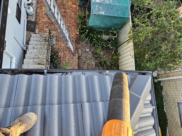A vacuum hose run along a corrugated roof gutter